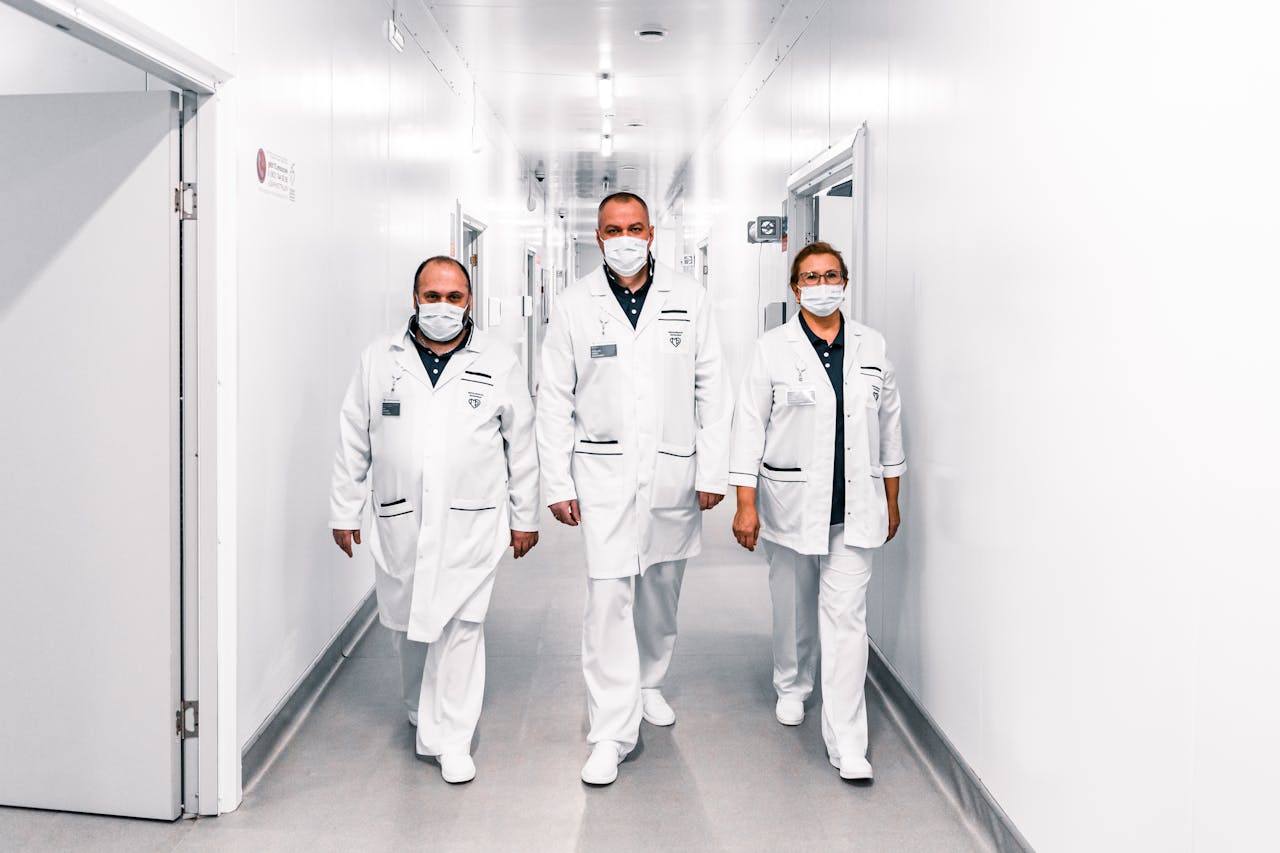 Team of doctors in face masks walking through a hospital corridor, showcasing teamwork and safety.